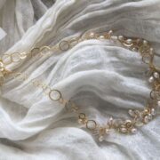collana girocollo argento dorato perle nome Mizar distesa su sciarpa bianca stropicciata