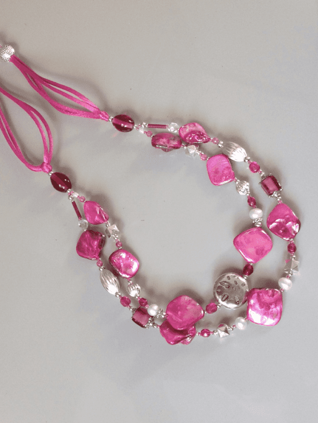 collana fucsia madreperla due fili perle agata cristalli di nome Luminosa Fucsia distesa sfondo grigio