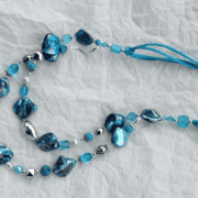 collana turchese madreperla due fili di nome Luminosa Turchese distesa carta bianca stropicciata