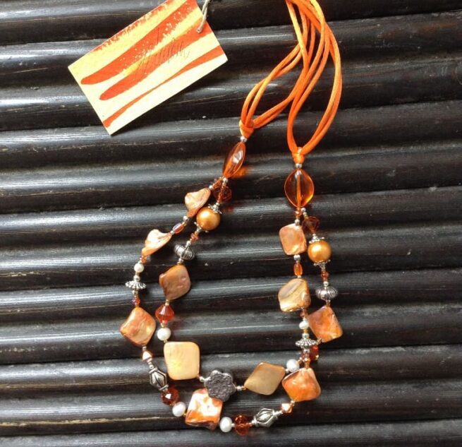 collana arancione madreperla due fili perle cristalli di nome Luminosa Arancione distesa sfondo legno nero