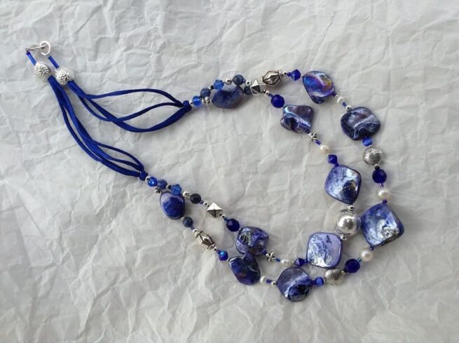 collana blu madreperla due fili pietre dure perle di nome LUMINOSA BLUETTE distesa carta bianca stropicciata