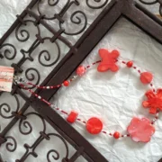 collana girocollo rossa ceramica nome Medea distesa su cornice ferro