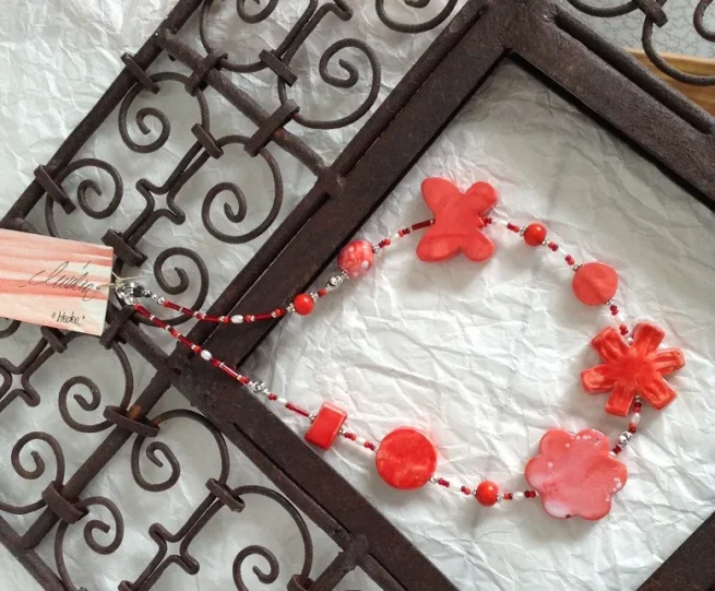 collana girocollo rossa ceramica nome Medea distesa su cornice ferro