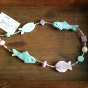 collana turchese lilla pesci ceramica lunga di nome Papeete distesa sfondo legno