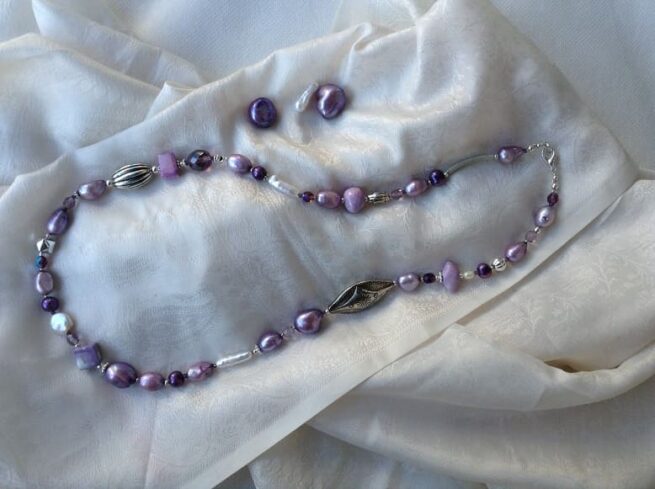 collana viola lunga perle ceramica nome Pensée distesa stoffa bianca