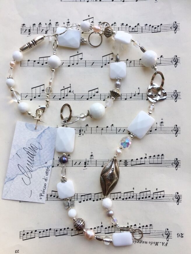 collana bianca lunga agata perle cristalli nome Fiocco di neve distesa su spartito musicale