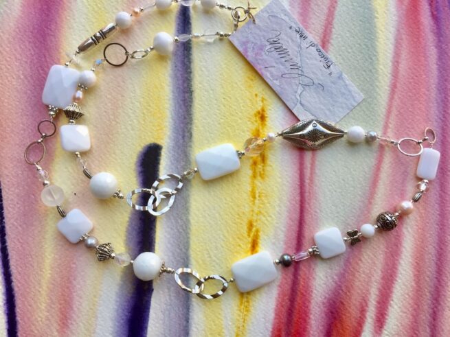 collana bianca lunga agata perle cristalli nome Fiocco di neve distesa su quadro colorato