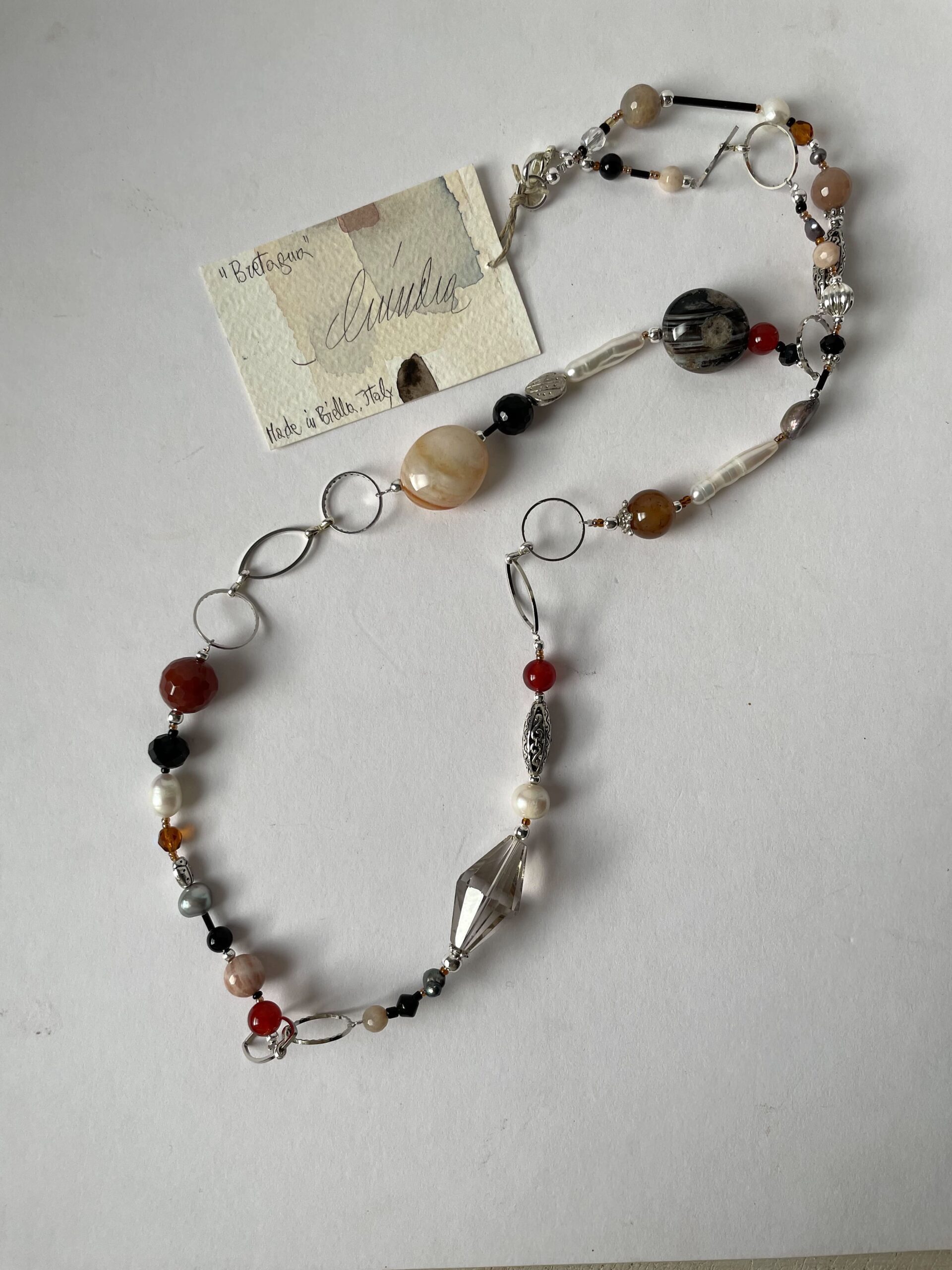 collana lunga in pietre di vari colori di nome Bretagna distesa sfondo bianco