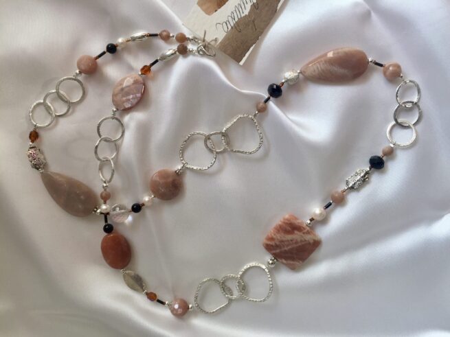 collana marrone lunga pietra luna onice nome Noce moscata distesa su seta bianca