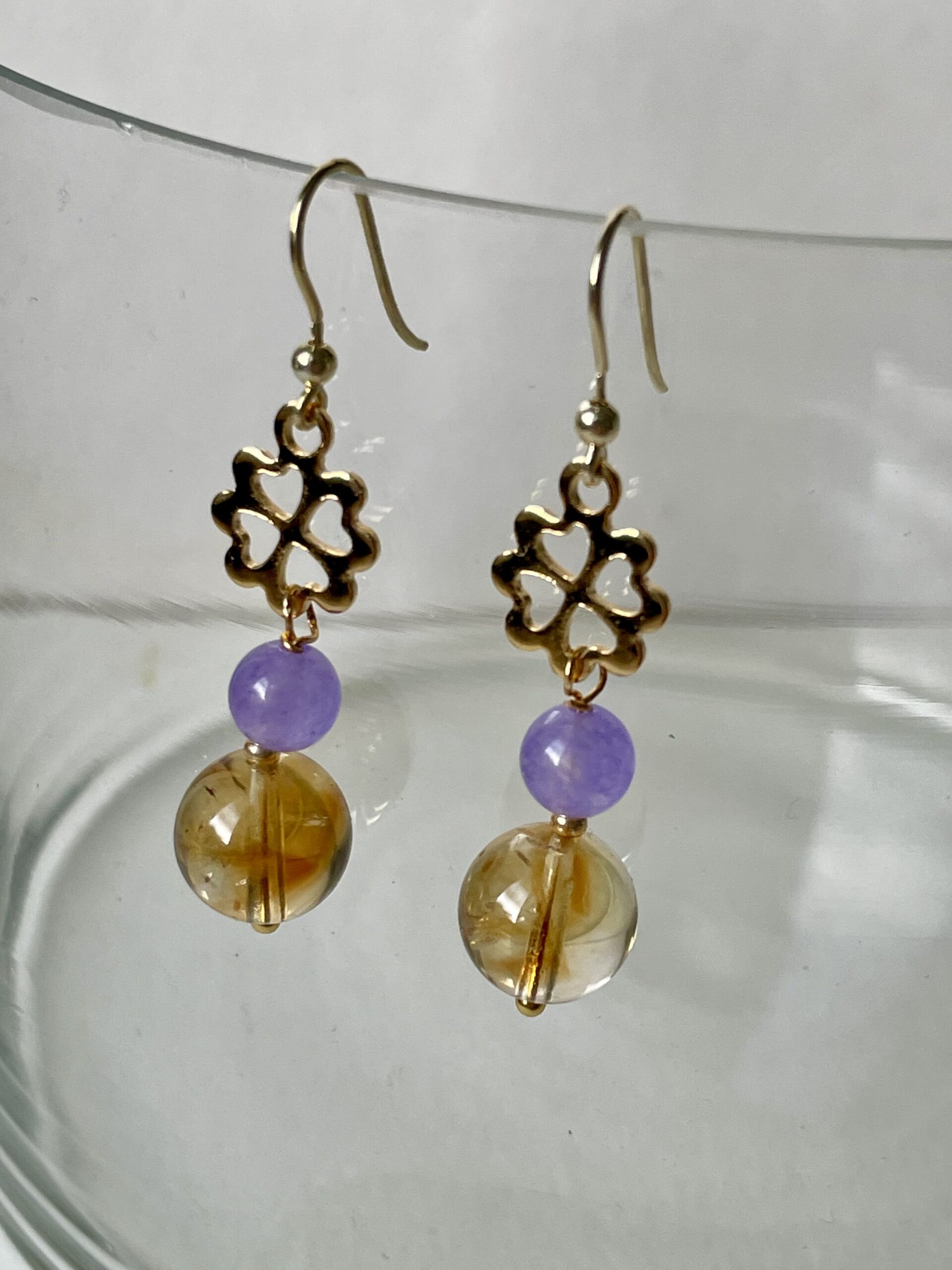 Orecchini citrino e agata lilla con quadrifogli di nome ORO di Napoli appesi vaso vetro