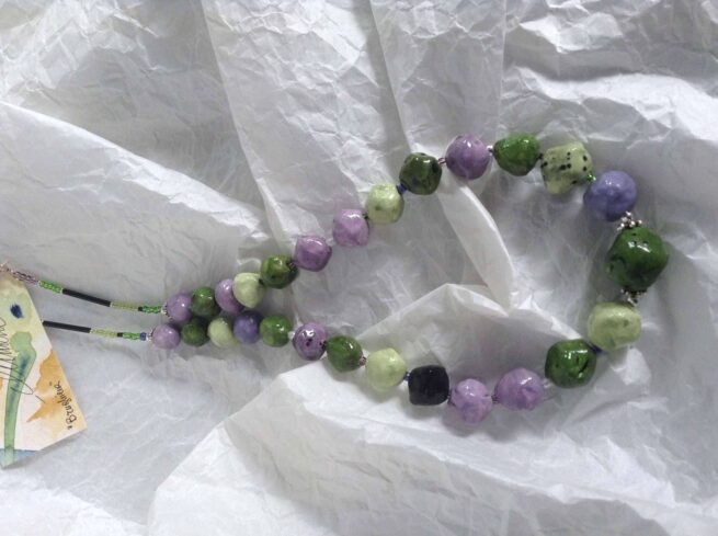 collana verde lilla ceramica chiamata Brughiera distesa su seta bianca