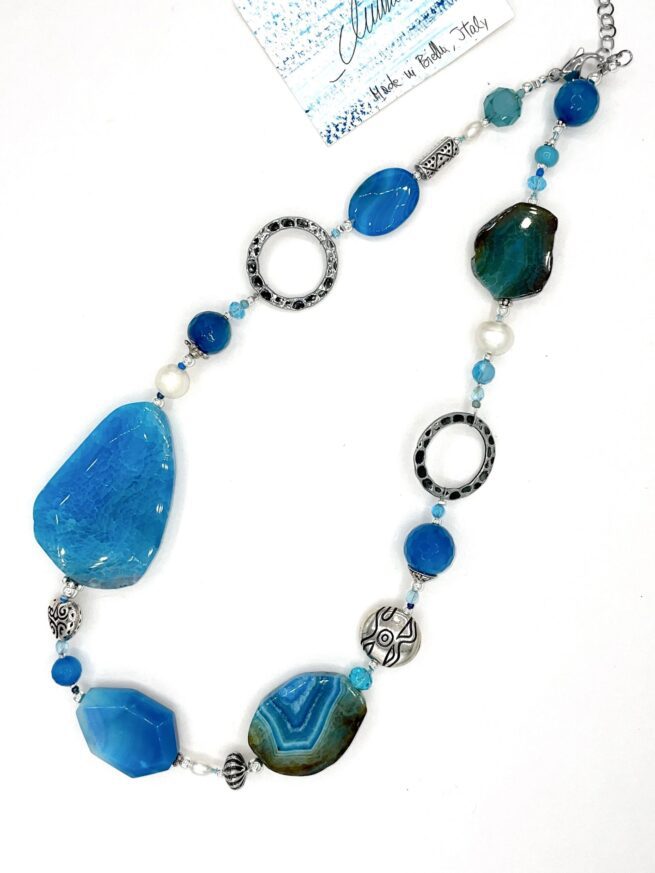 collana turchese pietre dure chiamata Deep Ice distesa sfondo bianco puro
