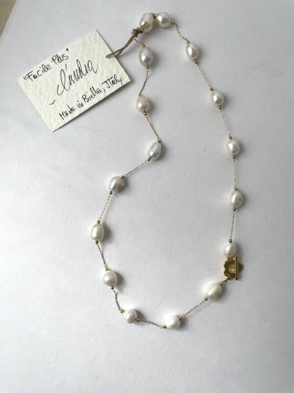 collana perle acciaio dorato chiusura fiore di nome Facile Plus distesa sfondo bianco